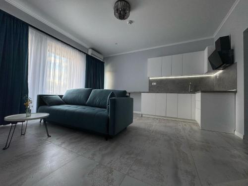 a living room with a blue couch and a kitchen at TisArt Hotel in Tismana