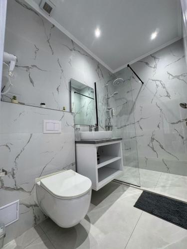 a white bathroom with a toilet and a sink at TisArt Hotel in Tismana