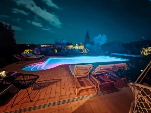 a swimming pool at night with chairs around it at Villa Rubix in Luz