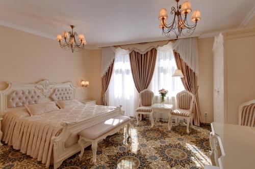 een slaapkamer met een wit bed en 2 stoelen bij Hotel Saint Petersburg in Karlsbad