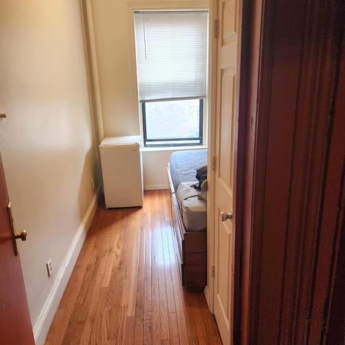 a small room with a bed and a window at New York City GuestHouse in New York