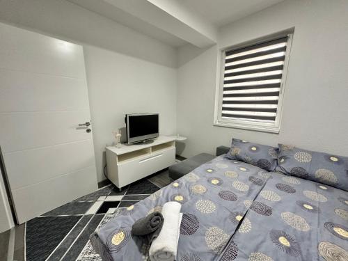 a small bedroom with a bed and a television at Apartman Zana in Visoko