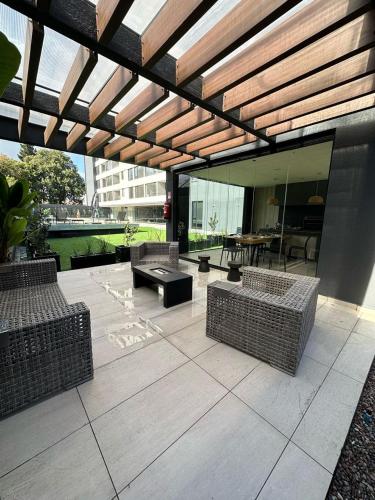 an outdoor patio with wicker chairs and a table at Vintage departamento in Los Ángeles