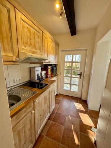 a kitchen with wooden cabinets and a tile floor at Hof Fetthörn, Ferienzimmer Muschel in Giekau