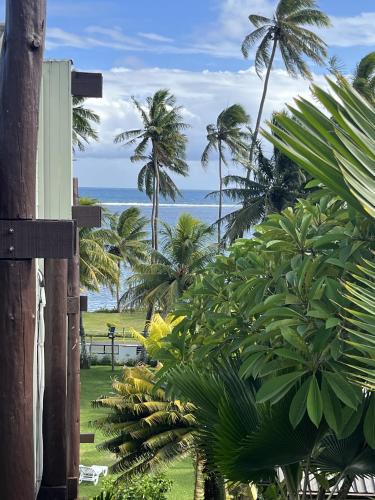 a view of a beach with palm trees and the ocean at The Crow's Nest Resort Fiji in Korotogo
