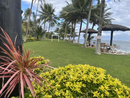 a park next to the beach with palm trees at The Crow's Nest Resort Fiji in Korotogo