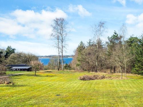 a field of grass with a house and a lake at 7 person holiday home in Skals-By Traum in Skals