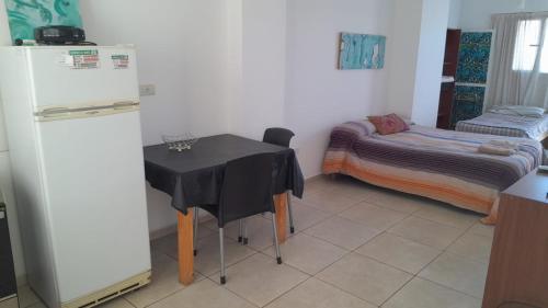 a kitchen with a table and a refrigerator and a bed at Centro in Neuquén