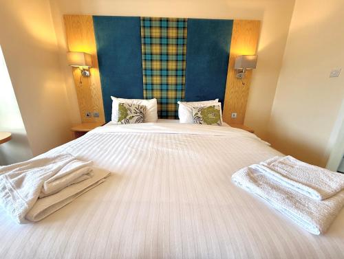a bedroom with a large white bed with towels on it at The Clubhouse Nairn in Nairn