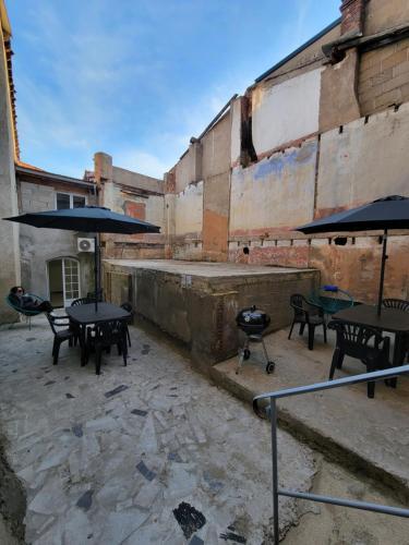 eine Terrasse mit Tischen und Sonnenschirmen in einem alten Gebäude in der Unterkunft Casa Bella - Borne arcade, Baby-Foot, Extérieur in Thiers