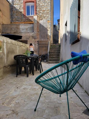eine grüne Bank auf einer Terrasse mit Tischen und Stühlen in der Unterkunft Casa Bella - Borne arcade, Baby-Foot, Extérieur in Thiers