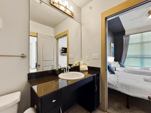 a bathroom with a sink and a bed and a mirror at Apartmint at Deep Ellum - Dallas in Dallas