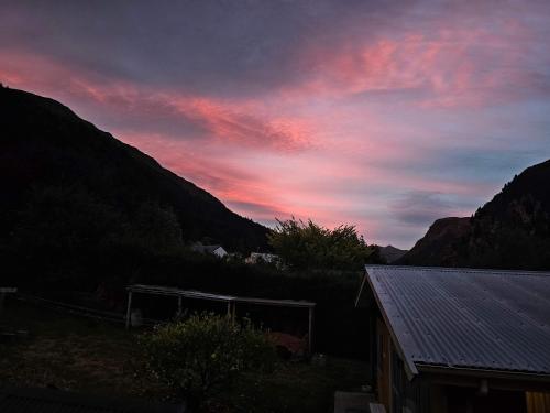 a sunset over a mountain with a house in the foreground at Apartment in the Heart of Queenstown in Queenstown
