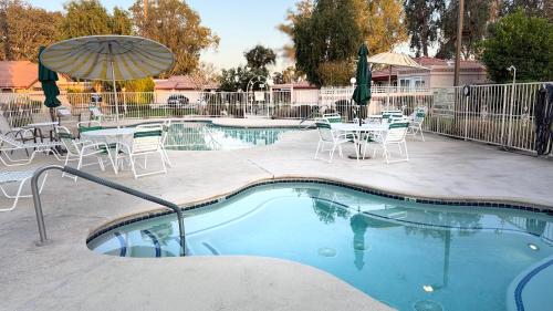 a pool with tables and chairs and an umbrella at Perfect Coachella Getaway! in Indio