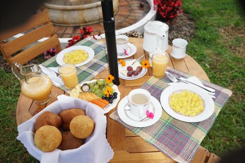 a table with plates of food and cups of orange juice at Hotel Campestre Casa La María in Firavitoba