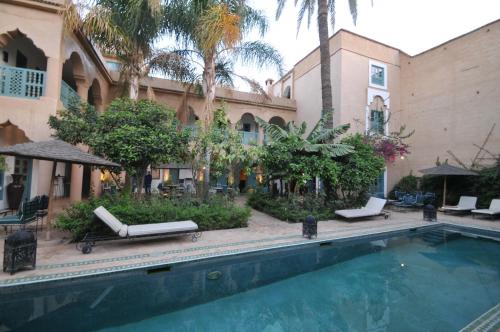 a swimming pool in front of a building with palm trees at Palais Oumensour in Taroudant