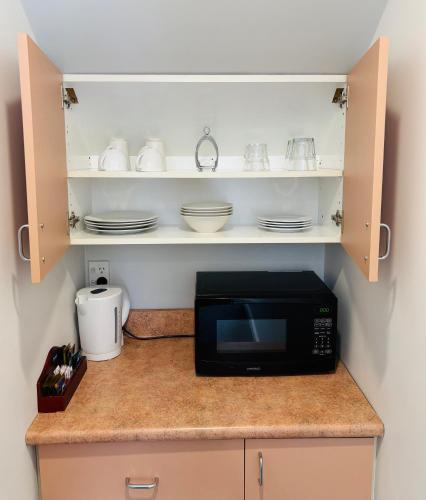 a kitchen counter with a microwave and dishes on a shelf at Bush Inn Court Motel in Christchurch