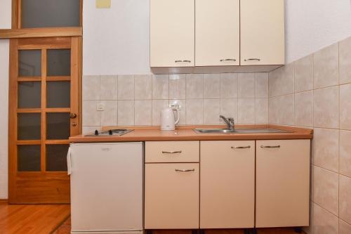 une cuisine avec des armoires blanches et un évier dans l'établissement Apartments by the sea Tucepi, Makarska - 23944, à Tučepi