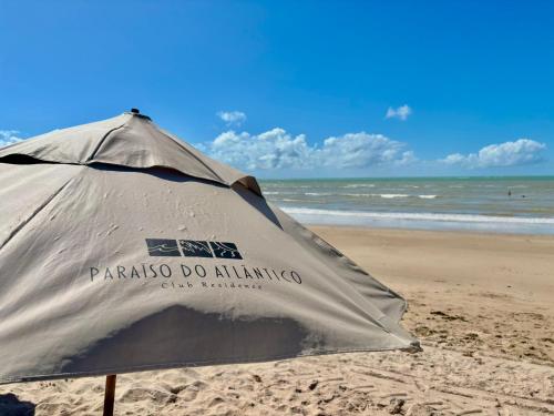 an umbrella on the beach with the ocean in the background at Viva o Paraíso – Condomínio Exclusivo Beira-Mar e Lazer Completo in Ilha da Restinga
