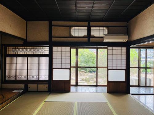 an empty room with doors and windows in a building at 1日1組限定 5LDKお洒落古民家 駐車場2台 夜景を望む宿 "一休庵" Traditional house with yard and parking in Hiroshima