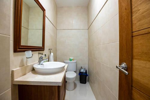 a bathroom with a sink and a toilet and a mirror at Pro Cab Paradise Condos Cabarete in Cabarete