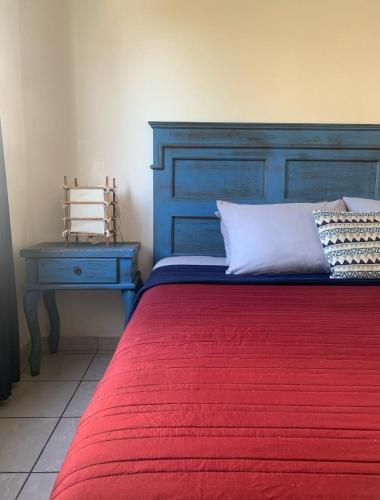 a bedroom with a bed with a blue headboard and a table at Bungalows La Perla in San Francisco