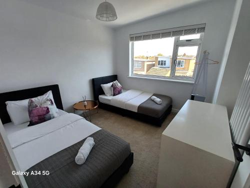 ein Schlafzimmer mit zwei Betten und einer Couch und einem Fenster in der Unterkunft Luxurious 3 Bedroom House in Kent