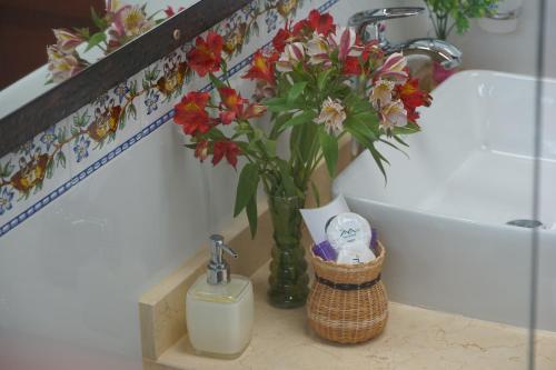 a vase with flowers on a shelf next to a sink at Hotel Campestre Casa La María in Firavitoba