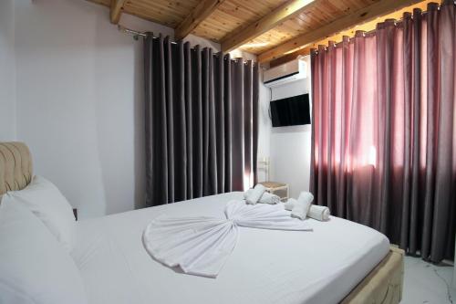 Schlafzimmer mit einem Bett mit weißer Bettwäsche und Vorhängen in der Unterkunft Seaside Vila Genti Pollo in Ksamil