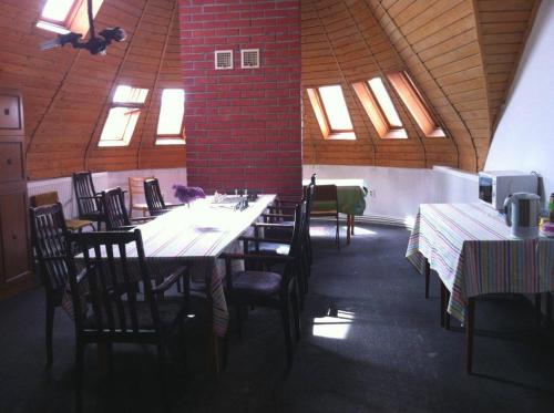 uma sala de jantar com mesas, cadeiras e janelas em Park Vendégház em Kecskemét