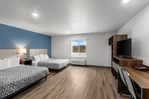 a hotel room with two beds and a desk with a television at WoodSpring Suites Beaverton - Portland West in Beaverton