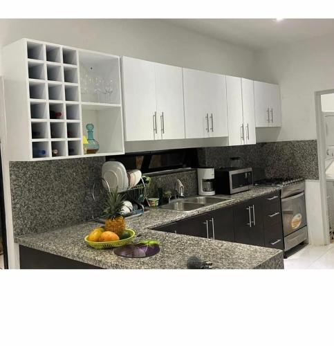 Una cocina con gabinetes blancos y un tazón de fruta en una encimera. en Villakeyden1, en Colorado