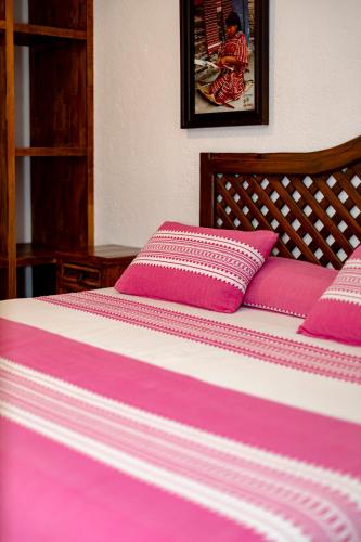 a bed with pink and white sheets and pillows at Hotel Casa Yunenisa in Oaxaca City