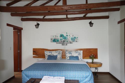 a bedroom with a bed with a blue comforter at Hotel Campestre Casa La María in Firavitoba