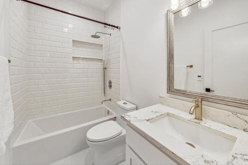a white bathroom with a tub and a toilet and a sink at Luxurious Lincoln Park Home with Gourmet Kitchen in Chicago