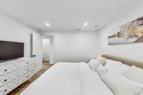 a white bedroom with a large bed and a flat screen tv at Luxurious Lincoln Park Home with Gourmet Kitchen in Chicago