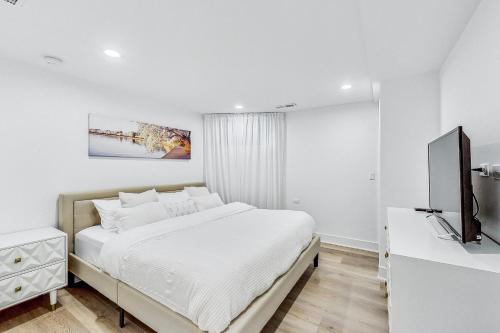 a white bedroom with a bed and a flat screen tv at Luxurious Lincoln Park Home with Gourmet Kitchen in Chicago