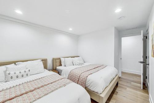 two beds in a room with white walls and wood floors at Luxurious Lincoln Park Home with Gourmet Kitchen in Chicago