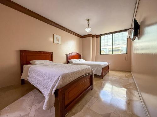 a bedroom with two beds and a window at Hotel Bucaneiro in Manta