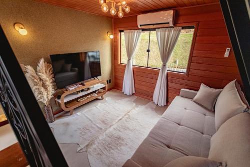 een woonkamer met een bank en een tv in een kamer bij Kleines Paradies Chalés in Massaranduba