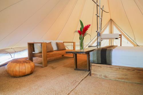 a tent with a couch and a vase with a flower on a table at Nómada Tayrona Boutique Glamping in Santa Marta