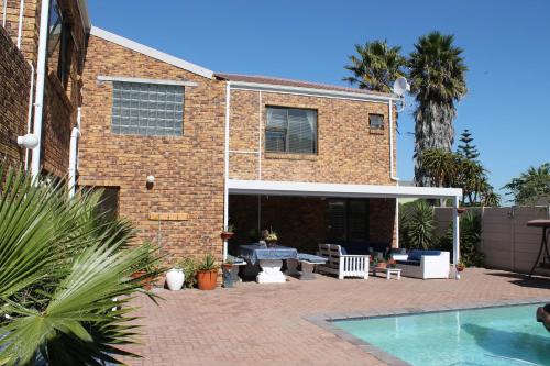 a brick house with a patio and a swimming pool at Quest Bed And Breakfast in Melkbosstrand