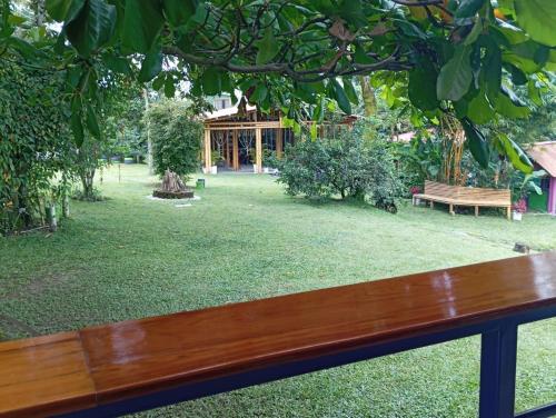 a wooden bench sitting under a tree in a park at Finca Hostal La Esperanza in Quimbaya