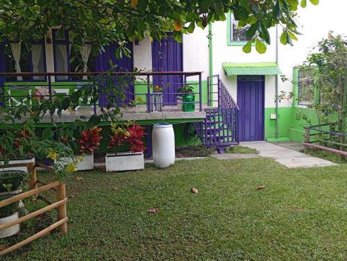 a house with a purple and green door and a yard at Finca Hostal La Esperanza in Quimbaya