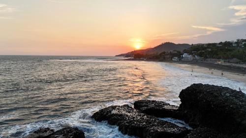 a sunset on a beach with rocks in the water at Eco del Mar in La Libertad