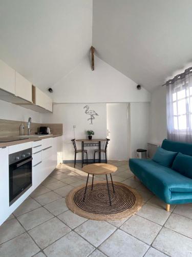 un salon avec un canapé bleu et une table dans l'établissement Petit gîte au coeur du haras, à Le Breuil-en-Auge