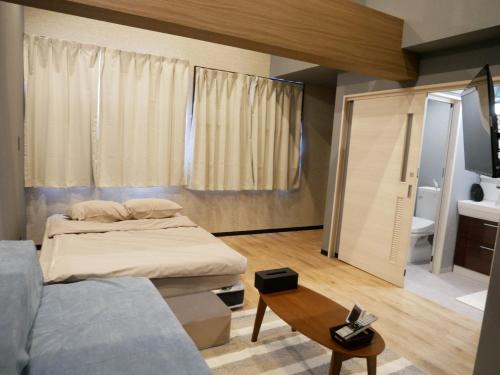a bedroom with a bed and a couch and a table at HOOD - Vacation STAY 19682v in Amami