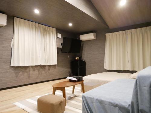 a bedroom with two beds and a table and a tv at HOOD - Vacation STAY 19696v in Amami