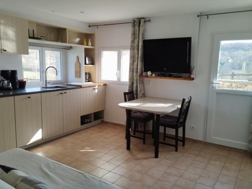 Il comprend une cuisine avec une table et des chaises ainsi qu'une télévision. dans l'établissement Le Domaine des Terres Blanches, à Le Boulvé