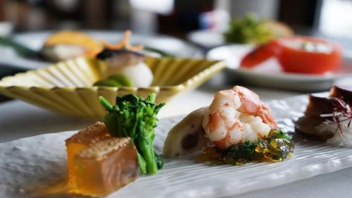 a plate of food with shrimp and broccoli on a table at Hotel Kikori in Hida